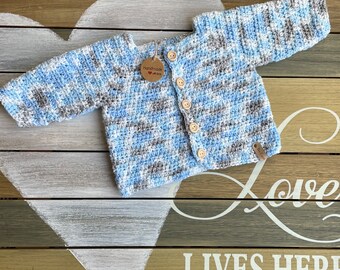 Crochet baby sweater in blue, grey, white with silver thread accents.