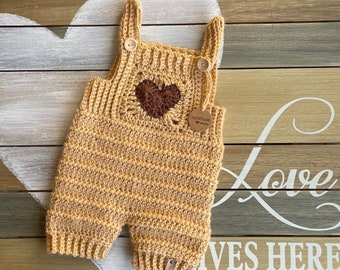 Crochet baby overalls / romper in corn silk beige with heart detail.