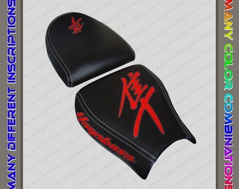 May include: Black motorcycle seat with red Hayabusa logo and text. The seat has white stitching and a matching passenger seat. The image also includes the text "HANDMADE", "MANY DIFFERENT INSCRIPTIONS", "MANY COLOR COMBINATIONS", and "1 YEAR WARRANTY".