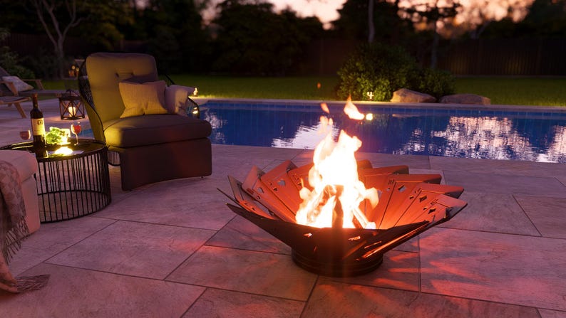 May include: A lit fire pit with a unique petal design sits on a patio near a pool. A chair, side table, and wine bottle are also visible. The scene is lit with warm, inviting light, suggesting an outdoor gathering.
