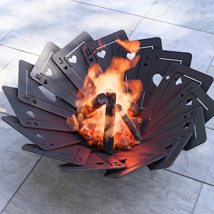 May include: A unique fire pit shaped like a fan of playing cards, with flames burning in the center. The cards are black with white suit symbols. The fire pit is made of metal and sits on a tiled surface.