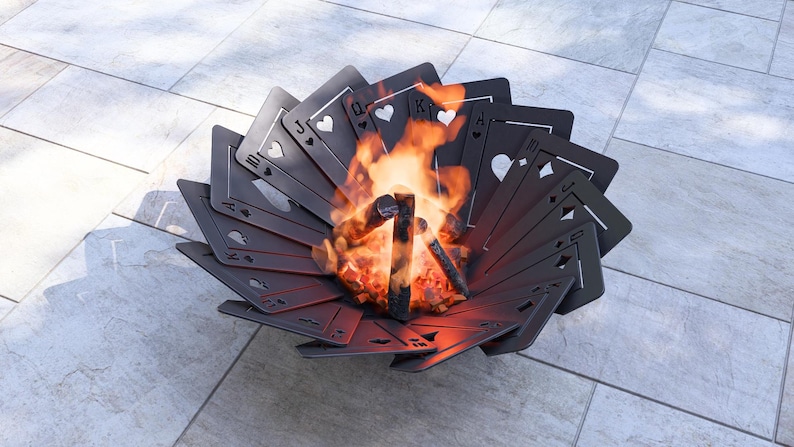May include: A unique fire pit shaped like a fan of playing cards, with flames burning in the center. The cards are black with white suit symbols. The fire pit is made of metal and sits on a tiled surface.