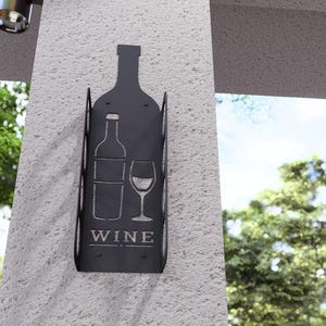 Puede incluir: Porta botellas de vino de metal negro con un dise&ntilde;o recortado de una botella de vino y un vaso. El porta botellas tiene la palabra "WINE" impresa.