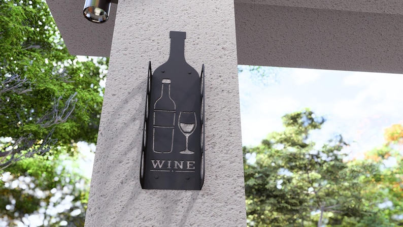 Puede incluir: Porta botellas de vino de metal negro con un dise&ntilde;o recortado de una botella de vino y un vaso. El porta botellas tiene la palabra "WINE" impresa.