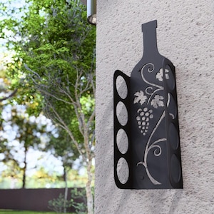 Puede incluir: Estante para botellas de vino de metal negro con dise&ntilde;o de vid. El estante tiene capacidad para seis botellas de vino y se monta en la pared.