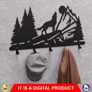 Puede incluir: Perchero de pared de metal negro con silueta de lobo aullando frente a un paisaje de montañas y pinos. Incluye cuatro ganchos. Una gorra gris y una chaqueta marrón cuelgan de los ganchos. El texto "IT IS A DIGITAL PRODUCT" está en la parte inferior.