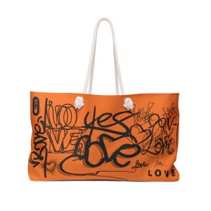 May include: Orange tote bag with white rope handles and black graffiti-style lettering that says "yes love" and "love" on the front.