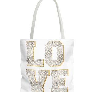 May include: White canvas tote bag with the word "LOVE" in gold outlined letters. The letters are filled with white pearl-like beads.