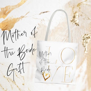 Puede incluir: Bolsa de tela blanca con letras doradas que dicen "Mother of the Bride" y "LOVE" con un coraz&oacute;n dorado en la esquina.