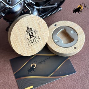May include: Two round wooden bottle openers with a metal bottle opener insert. One opener has a monogrammed design with the letter R and the text "RAHFELD".