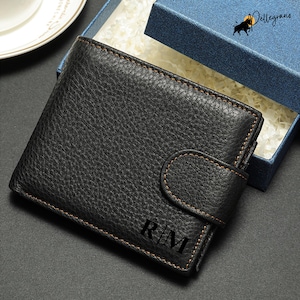 Può includere: Un portafoglio in pelle nera con chiusura a lembo e le iniziali "R.I.M." in rilievo sul davanti.