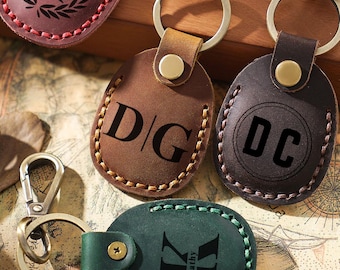 May include: Three leather keychains with different initials and designs. The first keychain is brown with the initials "D/G" in black. The second keychain is brown with the initials "DC" in a circle. The third keychain is green with the initial "K" and the name "Kathy" underneath.