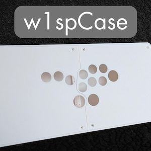 Może przedstawiać: Biała obudowa kontrolera do gier arcade w1spCase z wstępnie wywierconymi otworami na przyciski. Obudowa jest prostokątna z zaokrąglonymi narożnikami i wykonana jest z gładkiego, solidnego materiału. Tekst "w1spCase" jest wyświetlany w szarym prostokącie u góry.