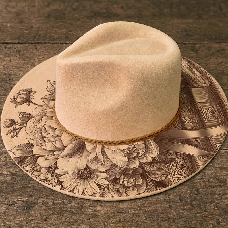 K&ouml;nnte beinhalten: Ein cremefarbener Hut im Fedora-Stil mit Blumen- und Buchdesign. Der Hut hat ein hellbraunes Seilband und eine breite Krempe. Die Krempe ist mit einem detaillierten Blumenmuster auf der linken Seite und einem Buchdesign auf der rechten Seite verziert.
