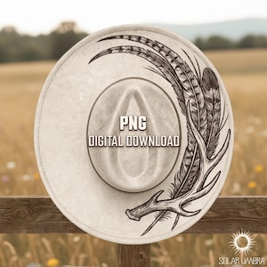 Op de afbeelding: Lichtbeige cowboyhoed met een decoratief zwart veren- en geweidesign. De hoed heeft de tekst "PNG DIGITAL DOWNLOAD". De hoed ligt op een houten hek.