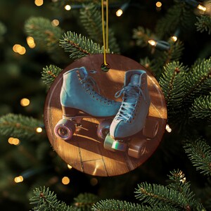 May include: A round wooden Christmas ornament featuring a pair of light blue roller skates. The skates have multi-colored wheels and are laced up. The ornament hangs from a gold string, with a blurred background of a Christmas tree.