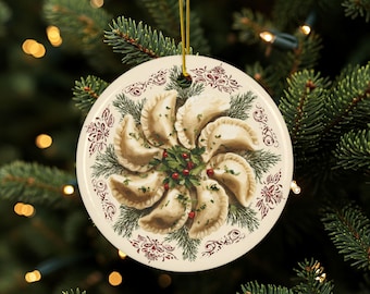 Puede incluir: Adorno navideño redondo con una ilustración detallada de pierogi dispuestos en círculo. El adorno tiene un fondo crema con un borde decorativo y una cuerda dorada para colgar. Los pierogi están rodeados de vegetación y bayas rojas.