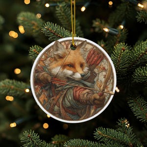 May include: A round Christmas ornament featuring a fox archer with a bow and arrow. The fox is depicted in a detailed, artistic style, with autumn leaves in the background. The ornament has a gold string for hanging.