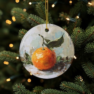 May include: Round Christmas ornament featuring a vibrant orange fruit with green leaves, painted in an impressionistic style. The ornament has a gold string for hanging. The background is a soft blend of colors, evoking a still life theme.