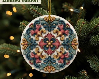 May include: A round, white Christmas ornament with a detailed, colorful floral design. The ornament features a symmetrical pattern in shades of teal, pink, and gold. The text "Limited Edition" is visible. The ornament hangs from a gold string against a backdrop of a Christmas tree.