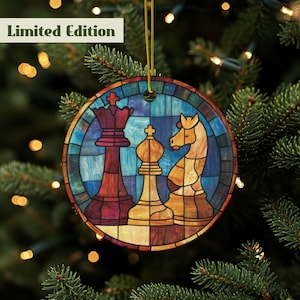 May include: Round wooden Christmas ornament featuring a stained-glass design of chess pieces: a king, a queen, and a knight. The ornament has a gold string for hanging and the words "Limited Edition" in a white box.