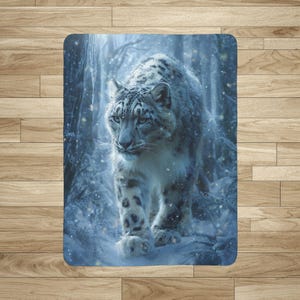 May include: A rectangular blanket featuring a snow leopard walking through a snowy forest. The snow leopard has a white and gray coat with black spots. The background shows a forest with snow-covered trees and falling snowflakes. The blanket has a blue and white color scheme.