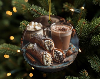 May include: Round Christmas ornament featuring a festive image of cannoli pastries, a cup of hot chocolate, and marshmallows. The ornament is round with a gold string for hanging. The background is a blurred Christmas tree.