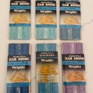 May include: Six packages of Flexi-Lace seam binding by Wrights in various colors. The packages display the product name, yardage, and color names like Aqua, Copen, Yale, Sapphire, and Orchid. Each package contains 3 yards of binding.