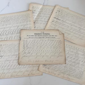 May include: A collection of antique handwritten documents, featuring faded ink on aged paper. The papers display cursive script and text, with some pages overlapping. The text includes the words "Schönschreib-Vorschriften" and dates from 1855.