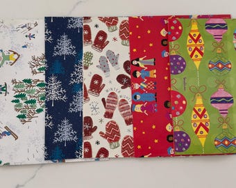 May include: A collection of six rectangular sheets of wrapping paper featuring various holiday designs including green foliage with the text PEACE LOVE, winter sports, white pine trees on navy, red mittens, figures on red, and colorful ornaments on green.