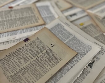 May include: A stack of vintage dictionary pages with the letter "G" highlighted. The pages are yellowed with age and have a worn, antique look.