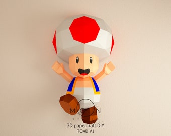 May include: A 3D papercraft DIY model of Toad from the Super Mario Bros. video game series. The model is made of paper and is painted in red, white, and blue. The model is in a standing position with arms raised and a happy expression. The text "3D papercraft DIY TOAD V1" is printed below the model.