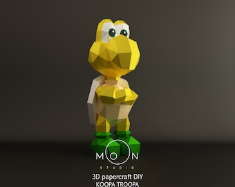 Op de afbeelding: Een 3D-papiermodel om zelf te bouwen van een Koopa Troopa uit de Super Mario Bros.-videogameserie. Het model is gemaakt van geel en groen papier en staat rechtop. Het model is een populair personage uit de videogameserie.