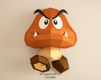 Op de afbeelding: Een 3D-papiermodel om zelf te bouwen van een Goomba, een paddenstoelachtige vijand uit de Super Mario-videogameserie. De Goomba is bruin met witte ogen en scherpe tanden en heeft een zwarte wenkbrauw.
