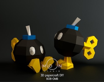 Könnte beinhalten: Zwei 3D-Papiercraft-DIY-Bob-Omb-Figuren. Die Figuren sind schwarz mit gelben und blauen Akzenten. Die Figuren stehen auf einer schwarzen Oberfläche. 3D papercraft DIY BOB-OMB