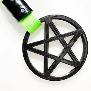 May include: A black pentagram charm with a green lanyard. The charm is a circle with a five-pointed star inside.