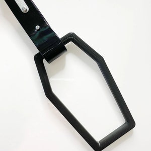 May include: Black plastic coffin-shaped keychain with a black leather strap and silver metal rivets.
