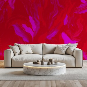 May include: A white sofa with two pillows sits in front of a wall with a red and pink abstract paint design.