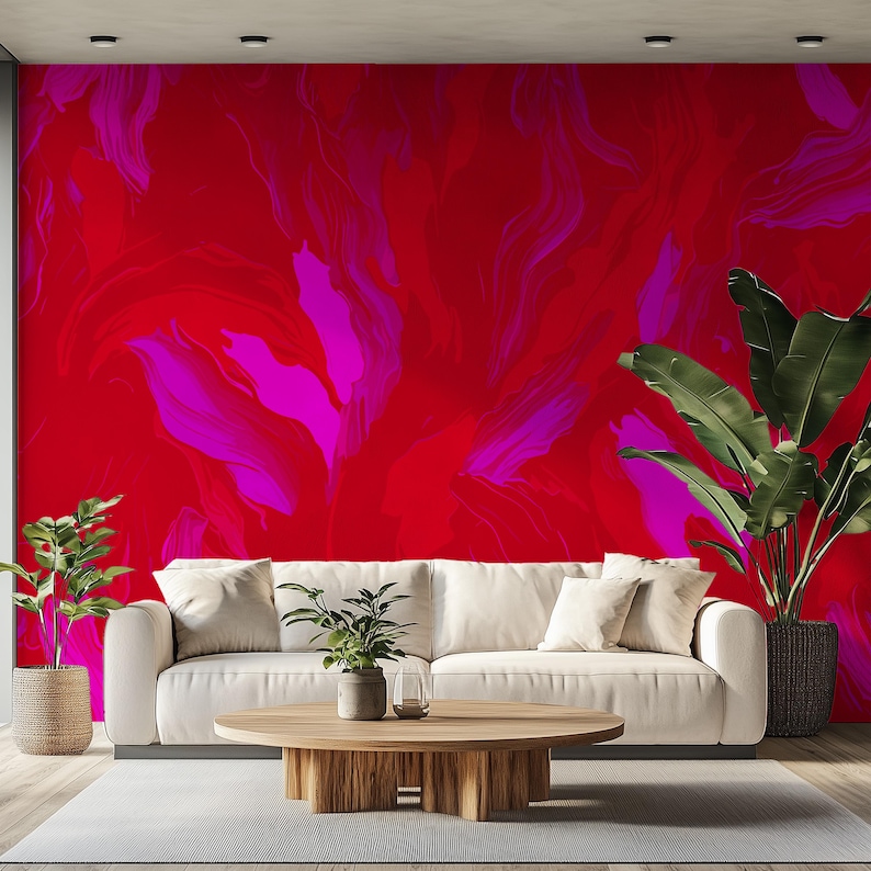 May include: A white sofa with pillows sits in front of a wall with a red and pink abstract painting. A potted plant sits on a wooden coffee table in front of the sofa.