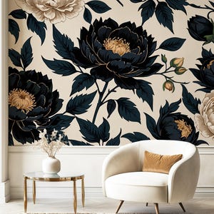 May include: A room featuring a floral wallpaper with large black and gold peonies and dark green leaves. A white armchair with a gold pillow and a small round table with a glass top and gold legs are in the foreground.