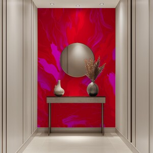 May include: A hallway with a red and pink abstract wall mural, a round mirror, a console table, and two vases with dried flowers.