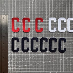 May include: Three sets of felt letter patches in red, white, and black. Each set contains the letter "C" repeated multiple times.