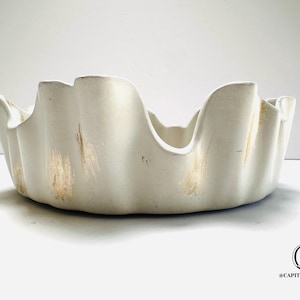 May include: White ceramic bowl with a wavy, scalloped edge. The bowl has a distressed, aged look with gold accents.