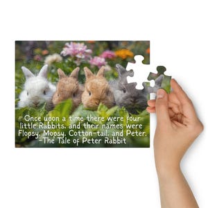 May include: A jigsaw puzzle depicting four rabbits amongst foliage. A hand holds a puzzle piece. Text on the puzzle reads: "Once upon a time there were four little Rabbits... -The Tale of Peter Rabbit."