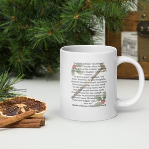 May include: White ceramic mug with a quote from Charles Dickens' A Christmas Carol. The quote reads, "And how did little Tim behave" asked Mrs Cratchit, when she had rallied Bob on his credulity and Bob had hugged his daughter to his heart's content. "As good as gold," said Bob, "and better. Somehow he gets thoughtful sitting by himself so much, and thinks the strangest things you ever heard. He told me, coming home, that he hoped the people saw him in the church, because he was a cripple, and it might be pleasant to them to remember upon Christmas Day, who made lame beggars walk, and blind men see."