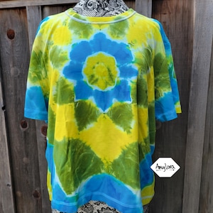 May include: A tie-dye t-shirt with a blue, yellow and green swirl pattern. The shirt has a crew neck and short sleeves.