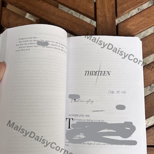Puede incluir: Libro abierto con la palabra "THIRTEEN" en gran fuente. Las p&aacute;ginas muestran texto y fechas, incluyendo "October 7th, 1998" y "October 9th, 1998". El libro est&aacute; sobre una superficie de madera.