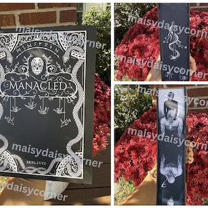 Puede incluir: Portada de libro negra con dise&ntilde;o blanco ornamentado, el t&iacute;tulo "MANACLED" est&aacute; centrado. El dise&ntilde;o incluye serpientes, una calavera y grullas de origami colgantes. El nombre del autor, SENLINYU, est&aacute; en la parte inferior. El libro se muestra al aire libre.