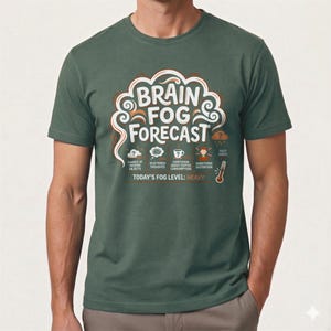 May include: A green t-shirt with the words "BRAIN FOG FORECAST" in white and orange. The design includes icons for symptoms such as "Chance of Forgetting Objects" and "Hazy Index." The text "TODAY'S FOG LEVEL: HEAVY" is also present.