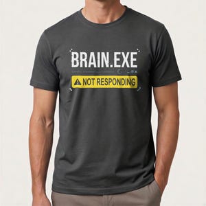 Pode incluir: Uma caneca de cerâmica branca com uma alça preta e o texto "But First, Coffee" em negrito preto. A caneca está sobre um fundo desfocado, sugerindo um ambiente acolhedor.